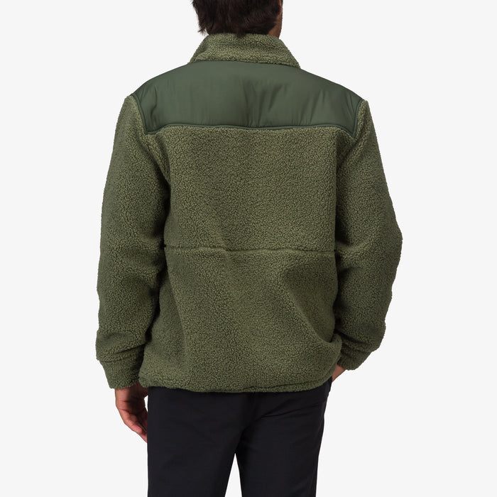 Back view of a man wearing an olive green Cooke Sherpa Jacket with a smooth shoulder panel, highlighting comfort and beach-inspired style.