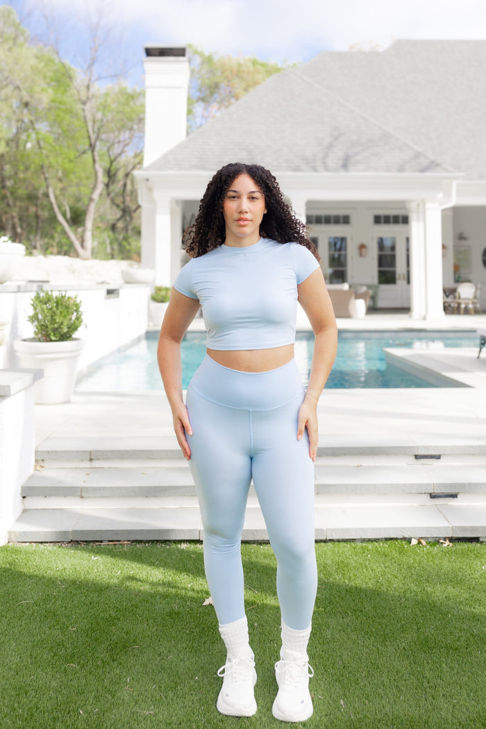 Female posing in front of a pool wearing the Bamboo Flex Baby Tee in Breeze with matching bamboo flex leggings
