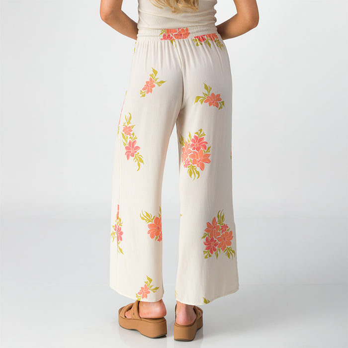 Woman wearing Belladona Pant with floral print, shown from back, paired with tan platform sandals facing backward.