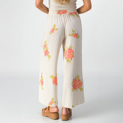 Woman wearing Belladona Pant with floral print, shown from back, paired with tan platform sandals facing backward.