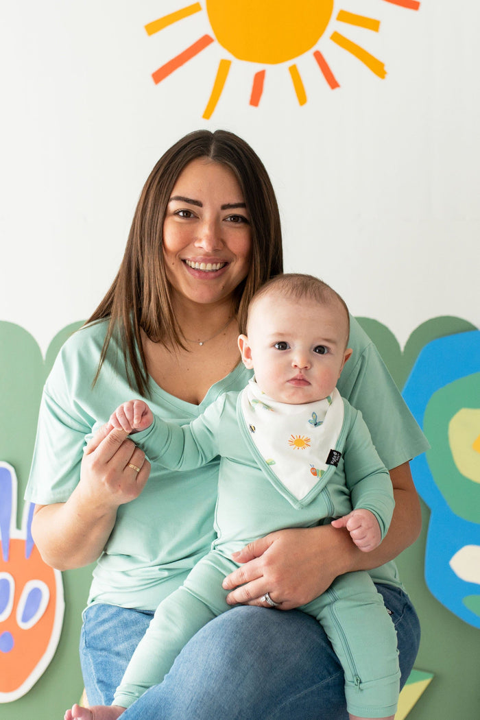 Mother wearing a green shirt holding her son who is matching and wearing a Bib in The Very Hungry Caterpillar™ and Friends