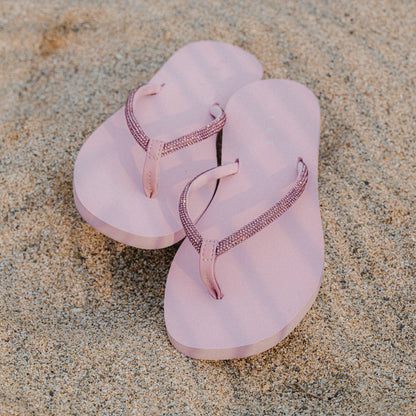 Bliss Bling Fling sandals facing forward, close-up of pink platform sandals with sparkling straps on sand beach
