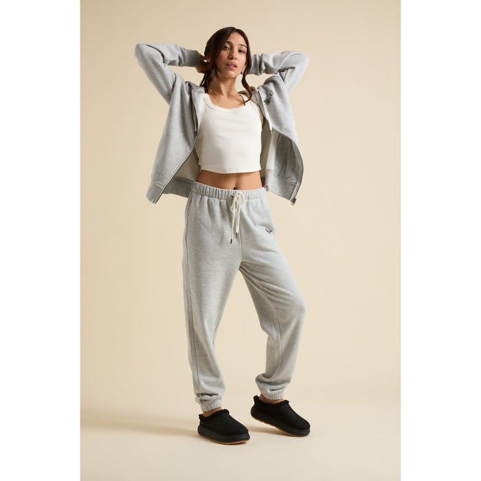 Woman wearing grey Brittany Fleece Full Zip hoodie facing forward with matching joggers and black slip-on shoes visible from the side.