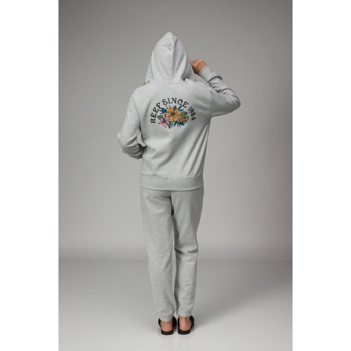 Rear view of a person wearing the Brittany Fleece Full Zip hoodie, featuring soft gray fabric and a floral REEF logo print.