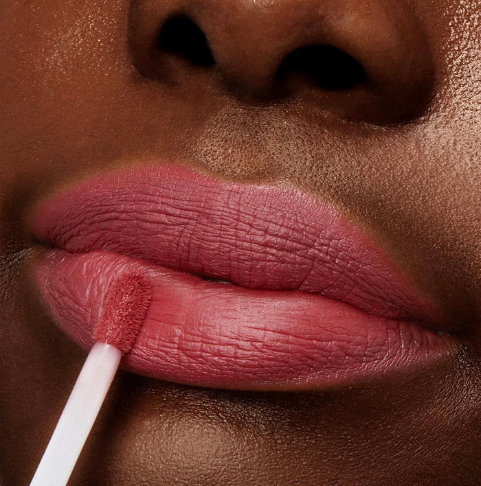 ColourPop Bumble Ultra Matte Lip liquid lipstick glides on with a doe-foot applicator, painting lips a warm rose-mauve, shown in an extreme close-up that spotlights the full-coverage, flat-matte finish.