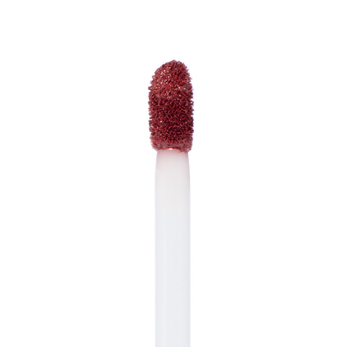 ColourPop Bumble Ultra Matte Lip doe-foot applicator depositing brick-rose liquid lipstick, close-up on a white background, highlighting the velvety formula and precision tip for smooth, long-wear application.