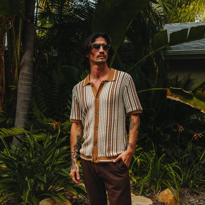 Man wearing Cabana Knit Sweater with vertical stripes in natural tones, styled for a beach-inspired casual look outdoors