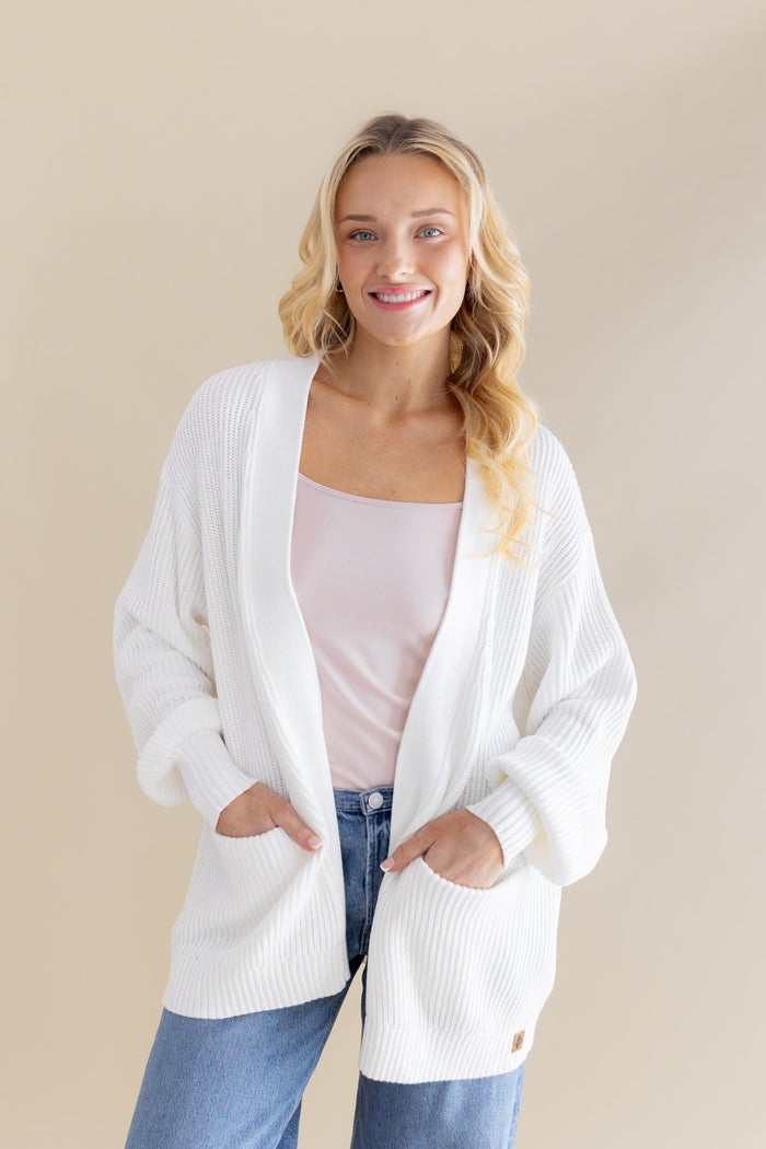 Female standing wearing the Chunky Knit Women's Oversized Cardigan in Cloud with both hands in the pocket