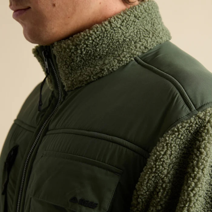 Close-up of the upper left side of the Cooke Sherpa Jacket showing olive green sherpa collar and fabric with chest pocket detail