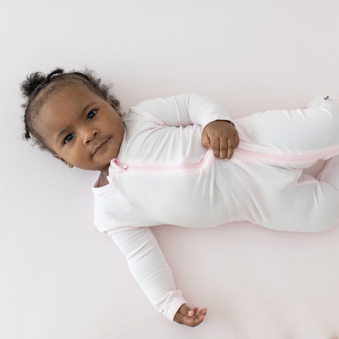 Infant laying on Kyte Baby bamboo Crib Sheet in Sakura