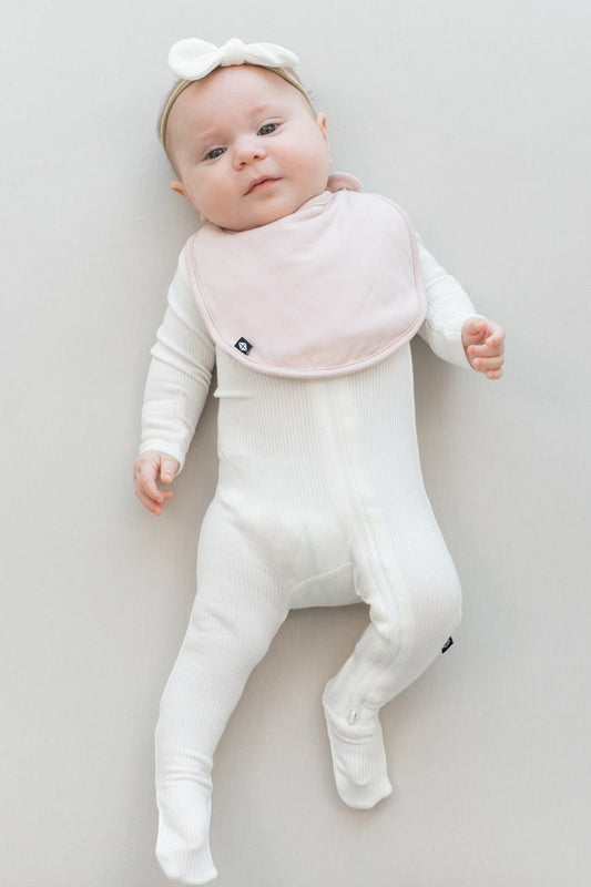 Infant wearing Kyte Baby Cushy Bib in Blush