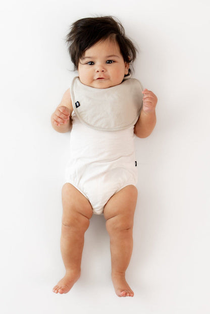 Infant wearing Kyte Baby Cushy Bamboo Bib in Oat