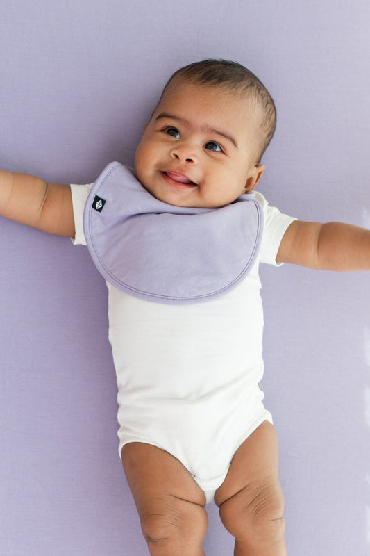 Infant wearing Kyte Baby Cushy Bib in Taro
