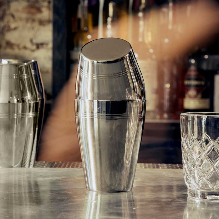 Silver cocktail shaker on a bar counter with blurred background