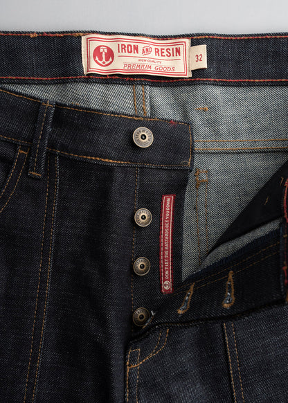 Close-up of Iron and Resin jeans with button fly, visible label, and red stitching detail, showcasing premium denim craftsmanship.