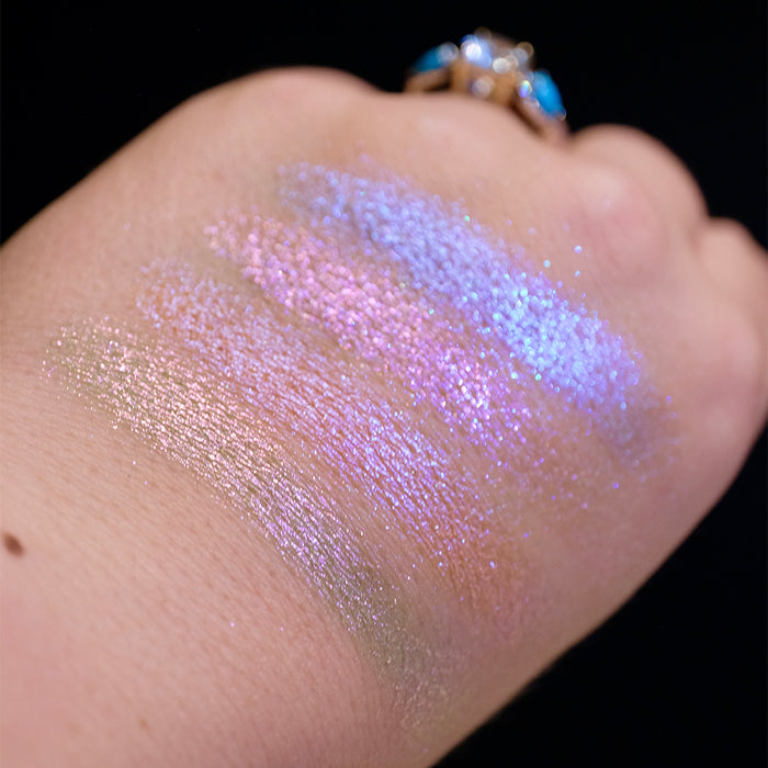 Swatches on the back of hand of all four shadows from the Glow Quad on fair skin tone with a black background.