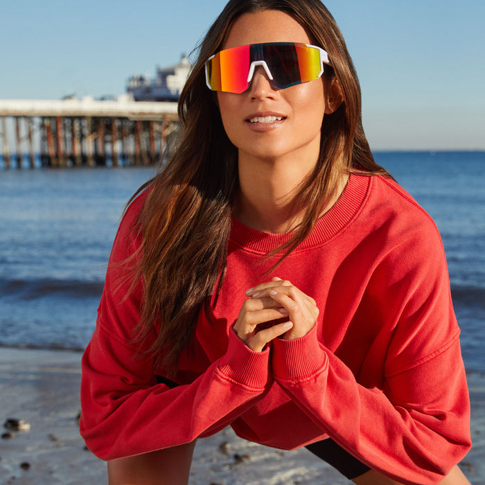 lifestyle - female playing volleyball at the beach wearing life style - female at the beach wearing diff sport heat shield sunglasses with a matte white frame and sunset mirror polarized lenses front view