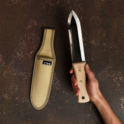 Hand holding a trowel next to canvas sheath on dark background