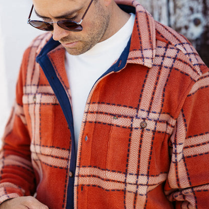 Man wearing a rust-colored Karter Shirt Jacket with plaid pattern, showing front upper torso and collar details.