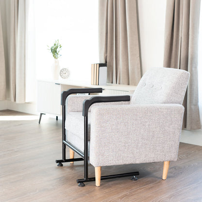 Gray armchair with black metal stand assist frame in a room with curtains and a clock.