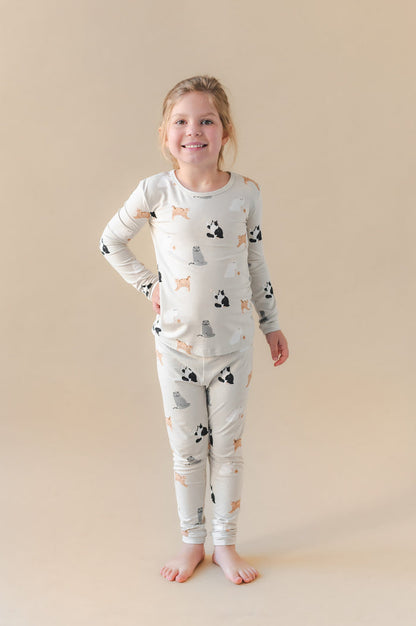 Young girl wearing a pajama set with cat prints on a beige background