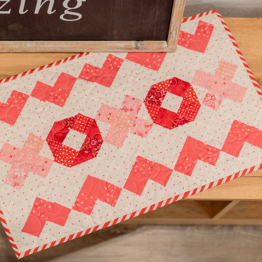 Quilt with red and pink pattern on a wooden surface