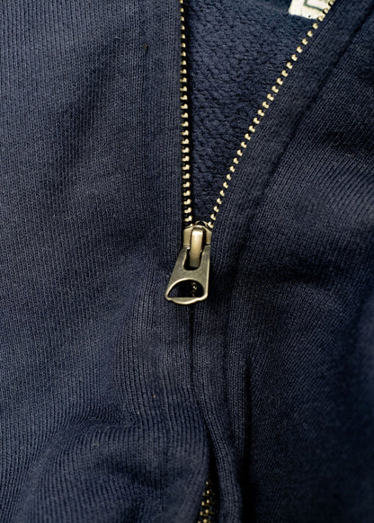 Close-up of a navy blue jacket with a partially open metal zipper, revealing a textured inner lining.