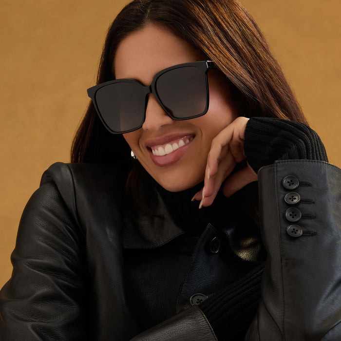 lifestyle - female wearing iconica diff eyewear naomi square oversized sunglasses with a black acetate frame and grey gradient polarized lenses angled view
