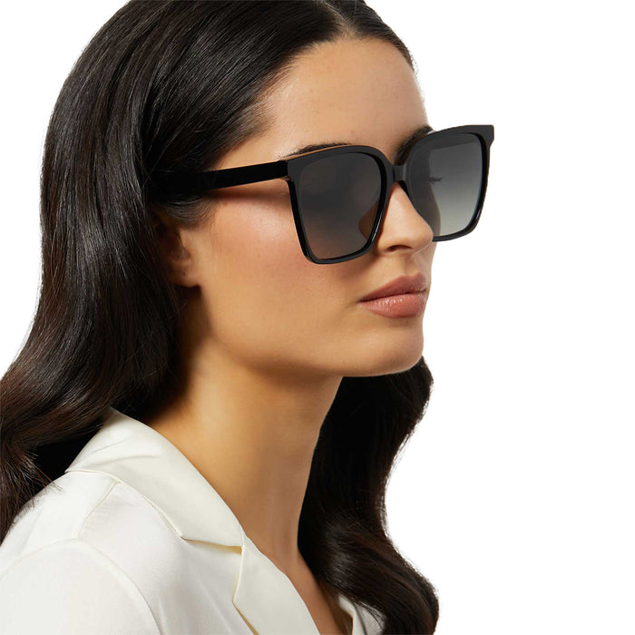 on model - female wearing iconica diff eyewear naomi square oversized sunglasses with a black acetate frame and grey gradient polarized lenses angled view