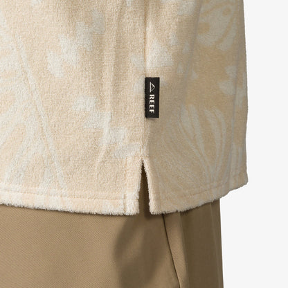Close-up of the lower side hem of the Novak Camp Shirt in beige terry fabric with REEF label, showcasing beach-inspired comfort.