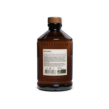 Back of brown glass bottle of passionfruit syrup with a wooden cap on a white background