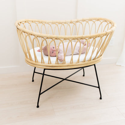 Baby laying on mattress covered with Kyte Baby Oval Bassinet Sheet in Cloud white