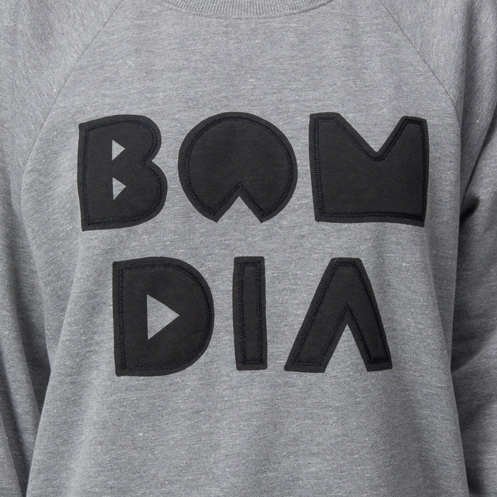 Close-up of the chest area on the women's Oversized Raglan Fleece in heather grey with bold black graphic letters.