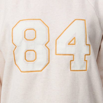 Close-up of the chest area of the women’s Oversized Raglan Fleece in oatmeal heather with embroidered number 84 detail.