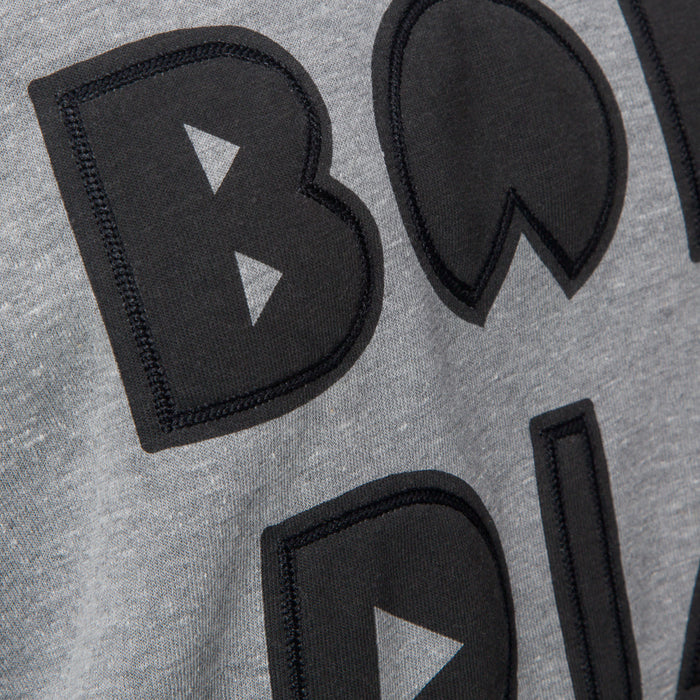 Close-up of the front chest embroidery on the Oversized Raglan Fleece in heather grey with soft, comfortable fabric.