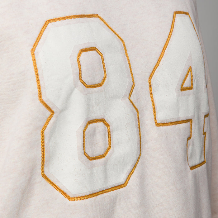 Close-up of oversized white and gold stitched numbers on front of women's Oversized Raglan Fleece, highlighting soft fabric texture.