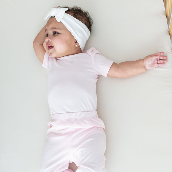 Infant wearing Kyte Baby Pants in Sakura pink