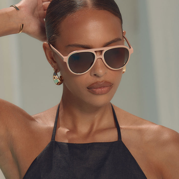lifestle - female at a resort wearing iconica x diff eyewear pia oversized aviator sunglasses with a nude acetate frame and brown gradient polarized lenses angled view