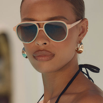 lifestle - female at a resort wearing iconica x diff eyewear pia oversized aviator sunglasses with a nude acetate frame and brown gradient polarized lenses front view