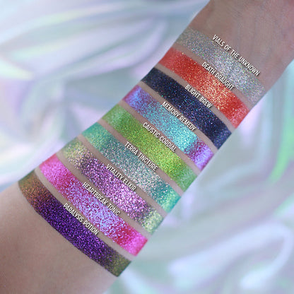 Swatches of all nine Pick Your Potion eyeshadows on pale coloured skin, on a white silky background.
