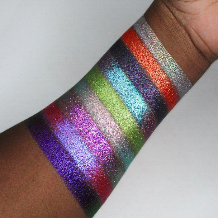 Swatches of all nine Pick Your Potion eyeshadows on deep coloured skin, on a white background.