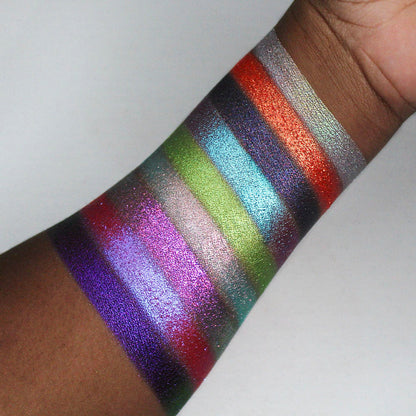Swatches of all nine Pick Your Potion eyeshadows on deep coloured skin, on a white background.