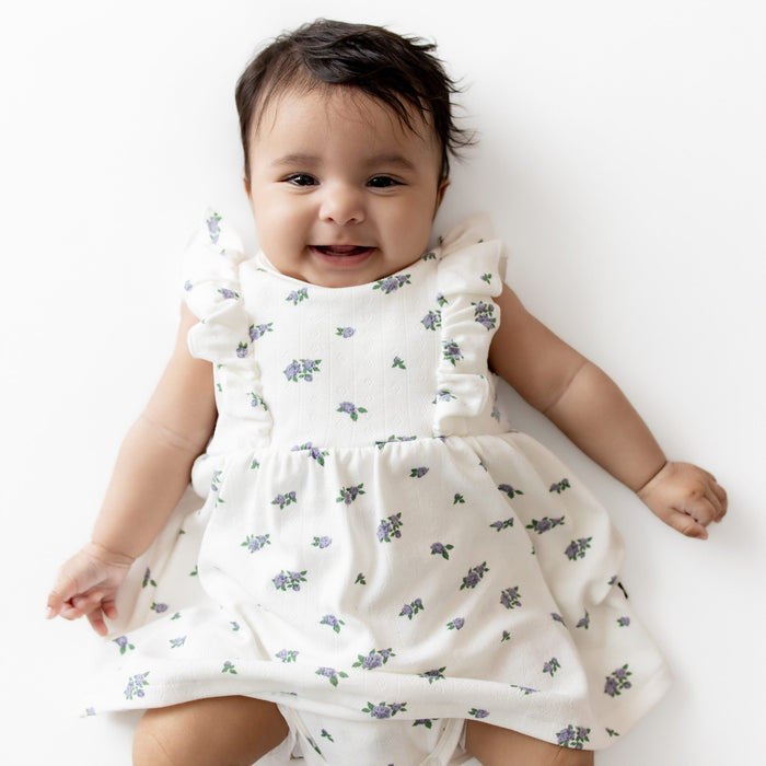 Baby wearing a white floral dress on a white background