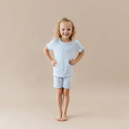 Young girl wearing a light blue pointellle lounge set on a beige background