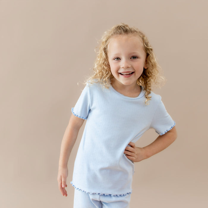 Young girl wearing a light blue pointelle  lounge set against a beige background