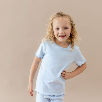 Young girl wearing a light blue pointelle  lounge set against a beige background