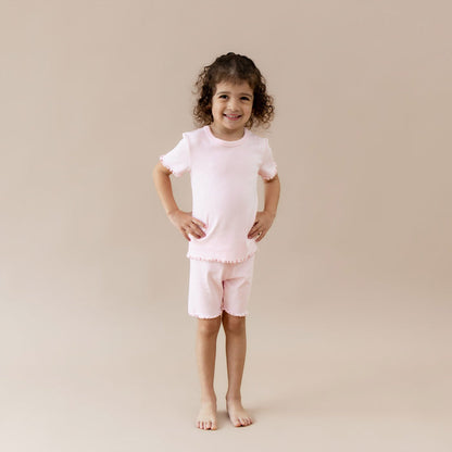 Child wearing a pink pointelle lounge outfit on a beige background