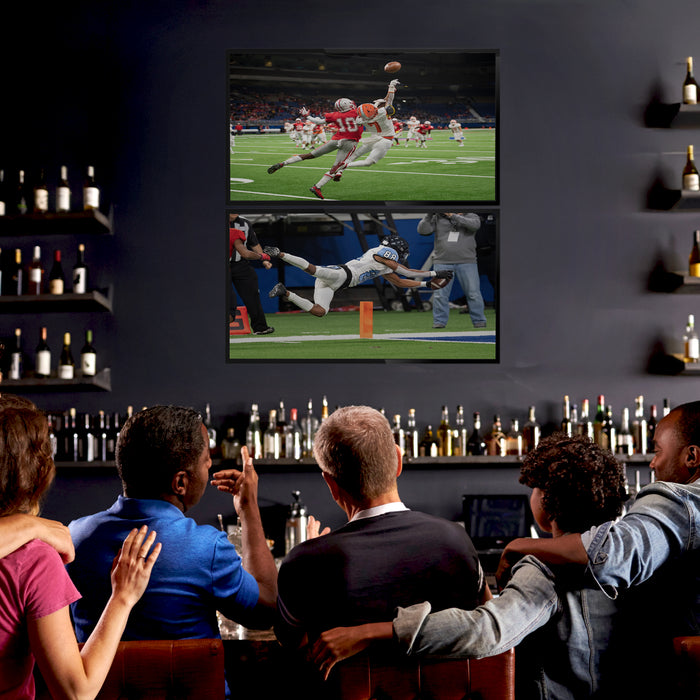 A black TV wall mount holding 2 TVs in a bar scene.