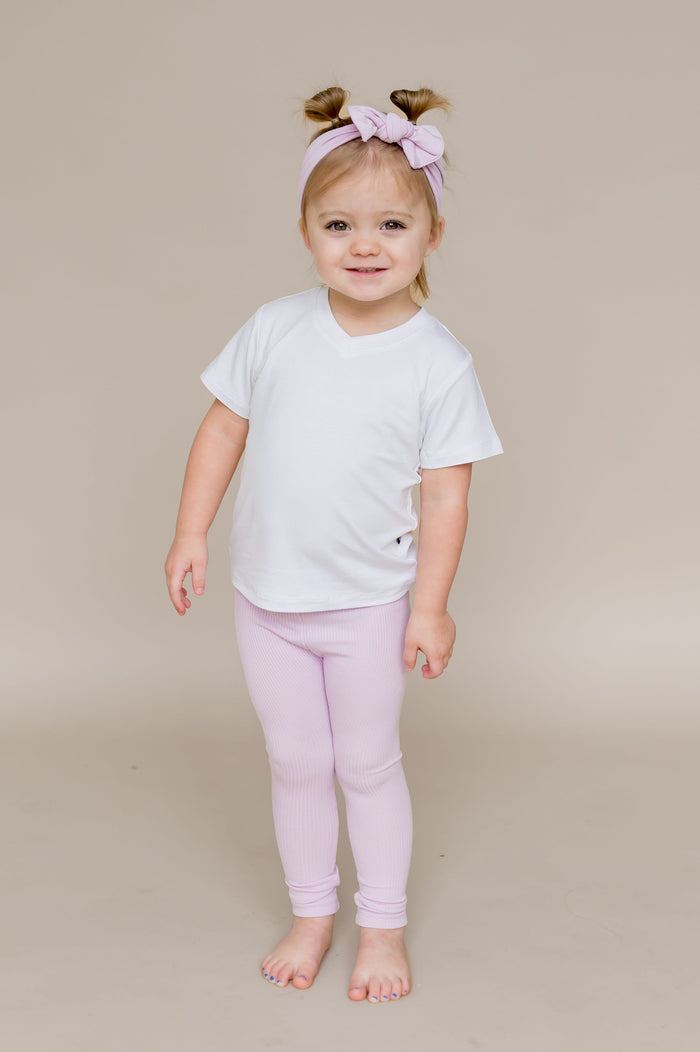 Young smiling girl wearing the Ribbed Leggings in Thistle paired with a white v-neck