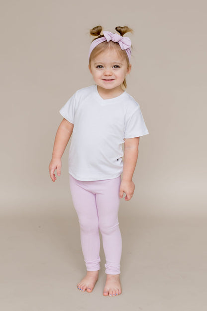Young smiling girl wearing the Ribbed Leggings in Thistle paired with a white v-neck
